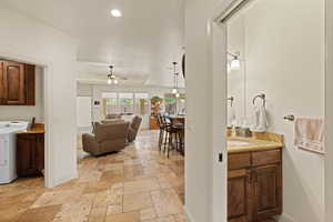 Hallway featuring washer / clothes dryer, a tray ceiling, and stone tile flooring