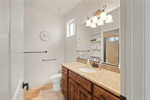 Full bathroom featuring vanity, a stall shower, and stone tile flooring