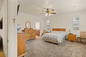 Bedroom with light carpet, multiple windows, a ceiling fan, and ensuite bathroom