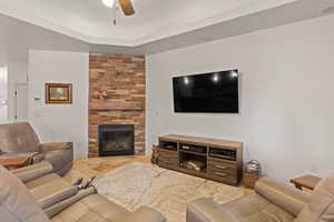Living room with a fireplace, ceiling fan, and a tray ceiling