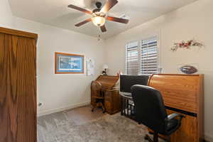 Office with light colored carpet and a ceiling fan