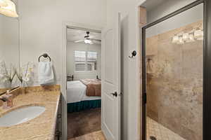 Full bath featuring a shower stall, vanity, ensuite bathroom, a ceiling fan, and light tile patterned floors