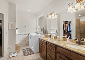 Full bathroom with a walk in closet, double vanity, a garden tub, tiled shower, and stone tile flooring