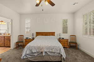 Bedroom featuring a ceiling fan, ensuite bathroom, and carpet