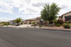 View of front of home featuring concrete driveway, stucco siding, stone siding, a garage, and a residential view