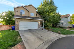 Traditional-style home with a garage, concrete driveway, stucco siding, and brick siding
