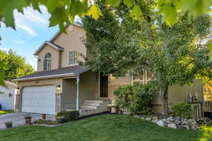 View of front facade featuring stucco siding, an attached garage, a front yard, driveway, and brick siding