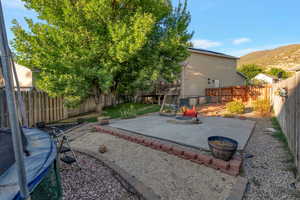 Fenced backyard with an outdoor fire pit, a patio area, and a deck with mountain view