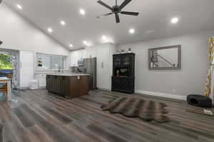 Kitchen featuring high vaulted ceiling, a center island, stainless steel appliances, dark wood-style floors, and ceiling fan