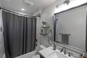 Bathroom featuring shower / bath combination with curtain, vanity, a textured ceiling, and recessed lighting