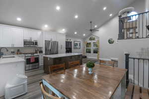 Dining room with a ceiling fan, recessed lighting, high vaulted ceiling, stairs, and light wood finished floors