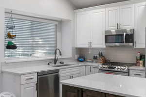 Kitchen featuring white cabinetry, appliances with stainless steel finishes, and light stone countertops