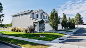 View of front facade with stucco siding, stone siding, a garage, driveway, and roof with shingles