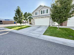 Traditional-style house featuring a front lawn, concrete driveway, an attached garage, and stucco siding