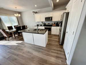 Kitchen featuring a center island with sink, appliances with stainless steel finishes, white cabinets, light wood-style flooring, and recessed lighting