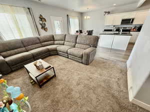 Living area with light carpet, plenty of natural light, a chandelier, and recessed lighting