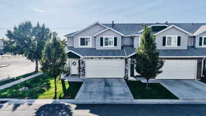 Traditional home with driveway, stucco siding, roof with shingles, and stone siding