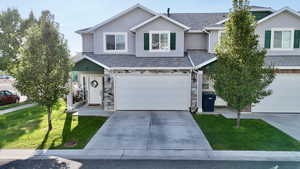 Traditional-style home featuring a front yard, driveway, stone siding, and a garage