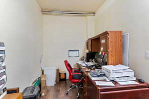 Home office featuring concrete block wall and dark wood-style floors
