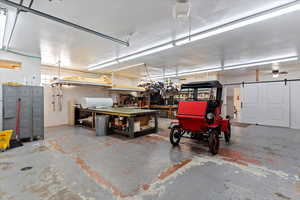 Garage featuring concrete block wall, a garage door opener, and a workshop area
