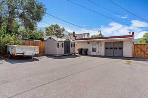 Single story home with a metal roof, an attached garage, stucco siding, and an outdoor structure
