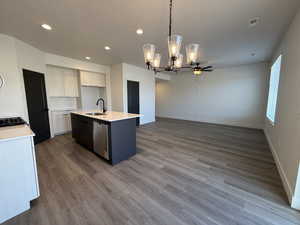Kitchen with hanging light fixtures, open floor plan, a center island with sink, a chandelier, and light wood-style flooring