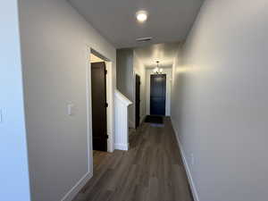 Hallway with dark wood-type flooring, a textured ceiling, and a chandelier