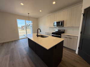 Kitchen with appliances with stainless steel finishes, modern cabinets, an island with sink, decorative light fixtures, and recessed lighting