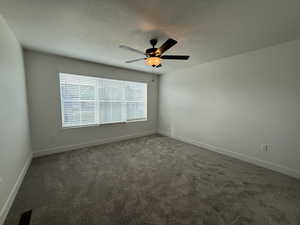 Carpeted spare room with a textured ceiling and a ceiling fan