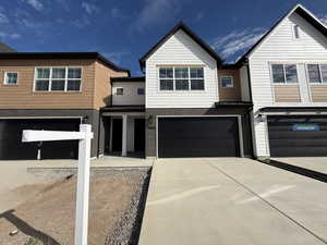 View of front of property with brick siding, concrete driveway, a garage, covered porch, and a standing seam roof