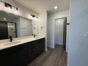Full bath featuring double vanity, a shower stall, dark wood-style floors, a textured ceiling, and recessed lighting