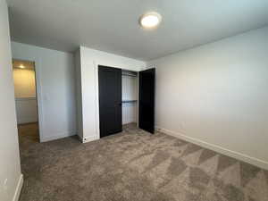 Unfurnished bedroom with carpet floors, a textured ceiling, and a closet