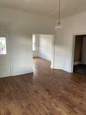 Unfurnished room with crown molding and dark wood-type flooring