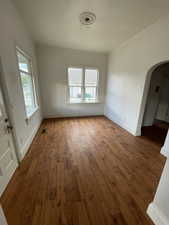 Unfurnished living room with arched walkways, hardwood / wood-style floors, and crown molding