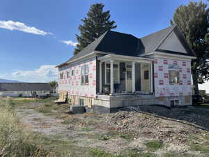 View of side of property with covered porch and roof with shingles