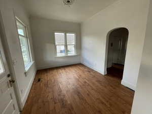 Spare room featuring arched walkways, wood-type flooring, and ornamental molding