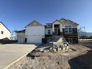 Craftsman-style home featuring board and batten siding, concrete driveway, an attached garage, stairs, and stone siding
