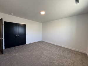 Unfurnished bedroom with a textured ceiling, dark carpet, and a closet
