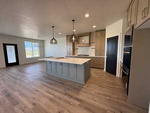 Kitchen featuring a spacious island, gray cabinets, tasteful backsplash, decorative light fixtures, and a textured ceiling