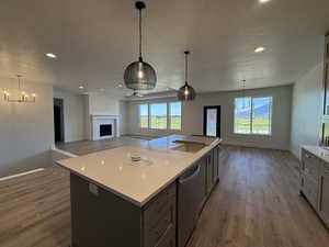 Kitchen featuring open floor plan, decorative light fixtures, a fireplace, a textured ceiling, and a kitchen island with sink