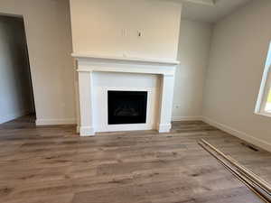 Unfurnished living room featuring a tile fireplace and wood finished floors