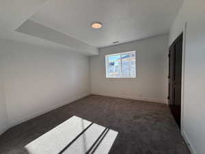 Unfurnished bedroom featuring dark carpet, a textured ceiling, and a closet