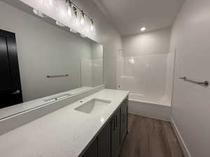 Full bath featuring vanity, dark wood finished floors, bathing tub / shower combination, and recessed lighting