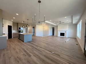 Kitchen featuring a kitchen island, gray cabinetry, open floor plan, light countertops, and decorative light fixtures