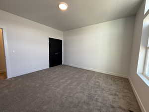 Unfurnished room featuring a textured ceiling and dark colored carpet