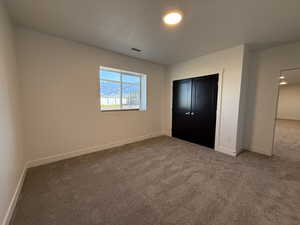 Unfurnished bedroom with dark carpet and a closet