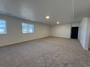 Empty room featuring light colored carpet, a textured ceiling, and recessed lighting
