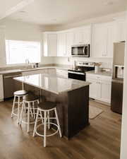 Kitchen with light stone counters, appliances with stainless steel finishes, white cabinetry, and recessed lighting