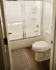 Bathroom with dark wood-type flooring and enclosed tub / shower combo