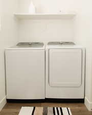 Washroom with dark wood-style floors and washer and clothes dryer